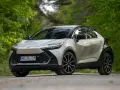Nowa Toyota C-HR 2025 w kolorze srebrno-czarnym, zaparkowana na leśnej drodze.