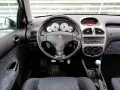 Wnętrze Peugeot 206 1.4 benzyna: kierownica, deska rozdzielcza z zegarami i radiem, dźwignia zmiany biegów, siedzenie.