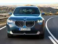 Nowy **BMW X3 2025** w kolorze granatowym jedzie krętą drogą pośród pustynnych krajobrazów.