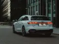Białe Audi A5 Avant z nowoczesnymi światłami LED na tle miejskiej architektury.