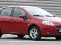 Czerwony Fiat Punto Evo z polskimi tablicami SB 2823E zaparkowany na szarym podłożu, z metalową ścianą w tle.