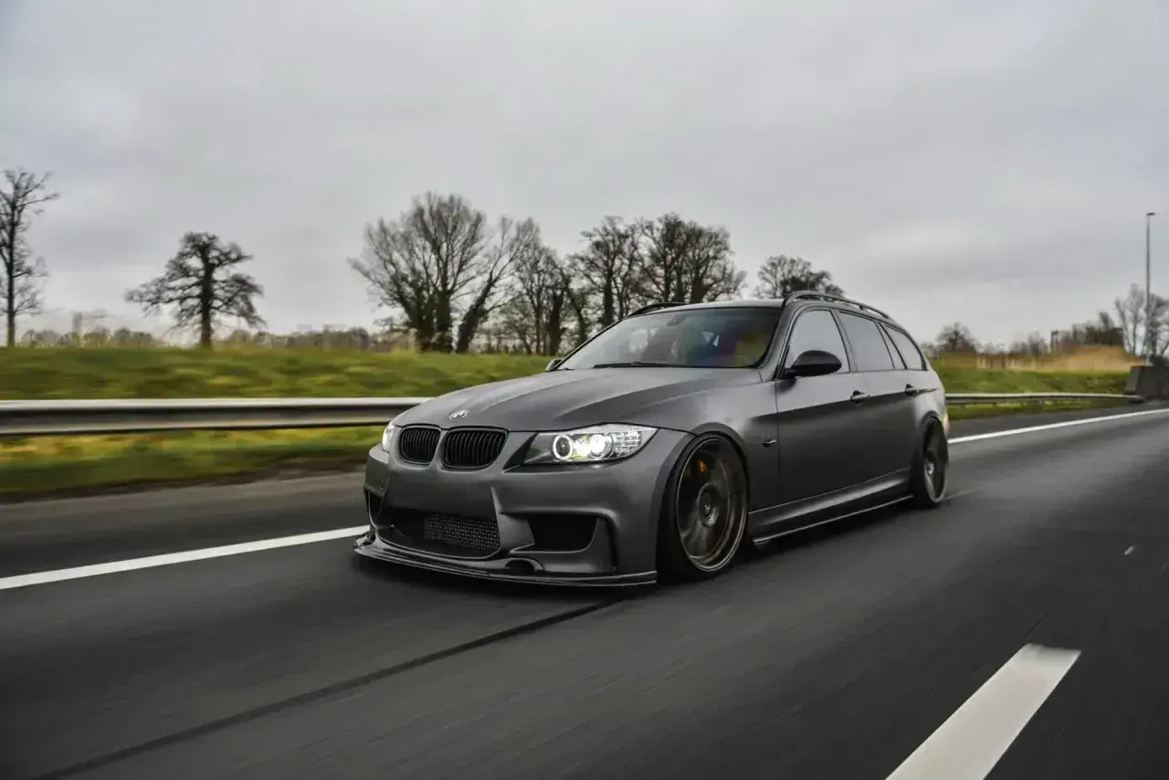 Szare BMW kombi pędzi autostradą, czuć jego prędkość.