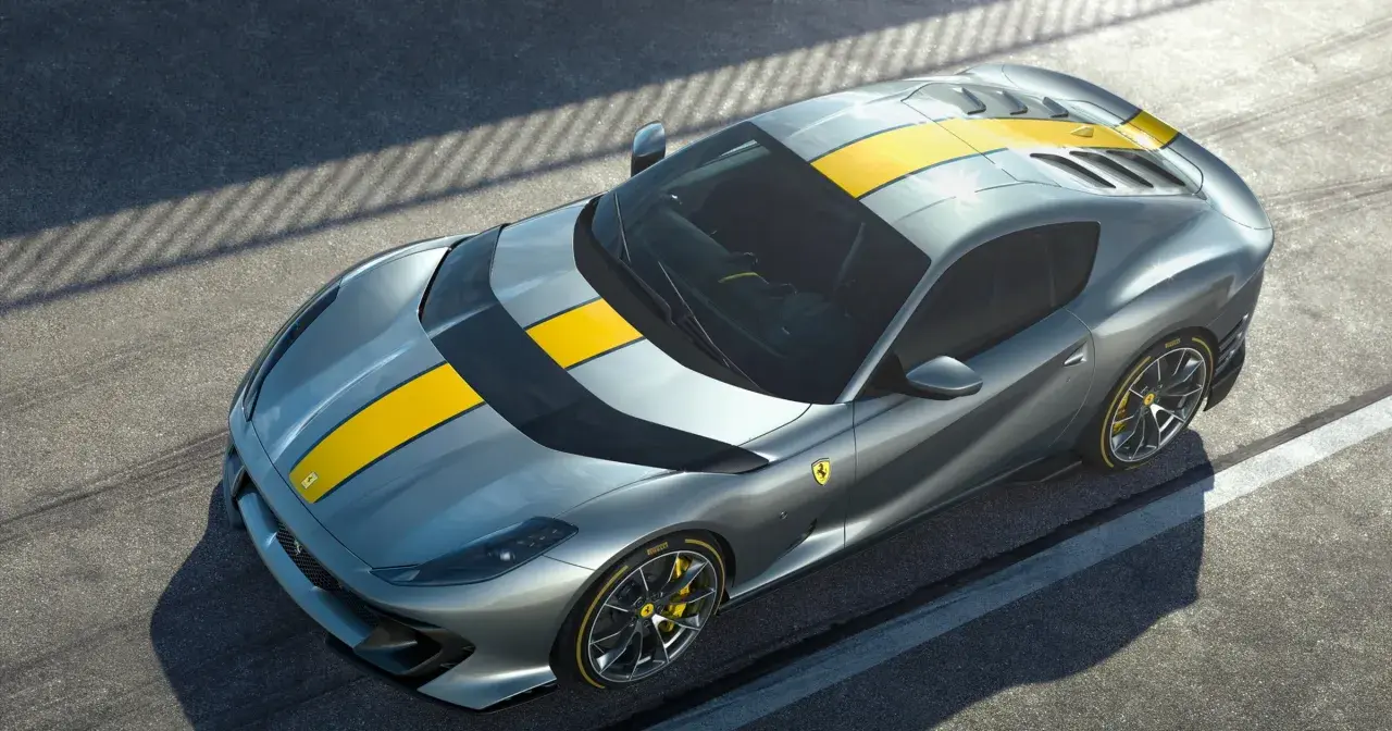 Szary Ferrari 812 Superfast z żółtymi pasami na masce i dachu, gotowy do szaleństwa na torze.