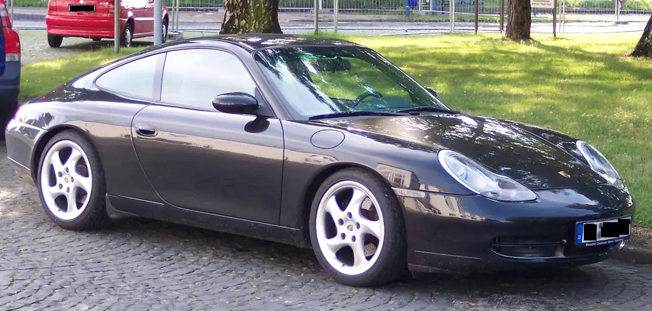 Czarny Porsche 996 z felgami w kolorze srebrnym stoi na bruku.