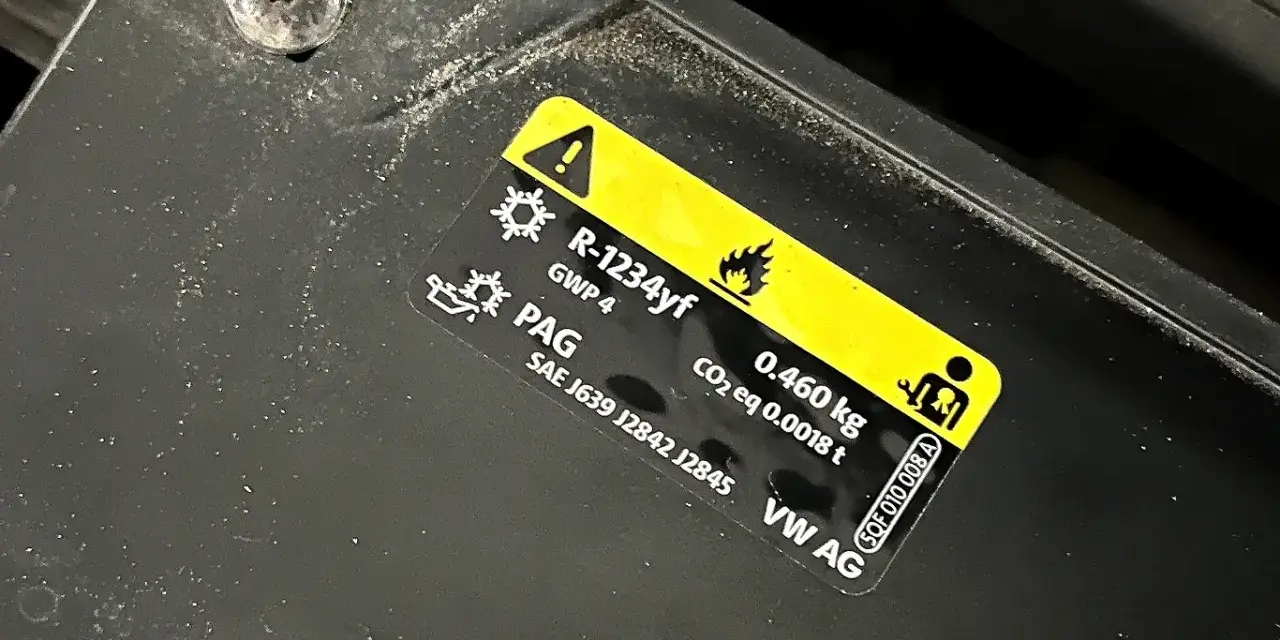 Naklejka informuje o ilości i typie czynnika chłodniczego R-1234yf (0.460 kg) w układzie klimatyzacji VW AG.