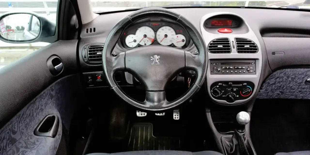 Wnętrze Peugeot 206 1.4 benzyna: kierownica, deska rozdzielcza z zegarami i radiem, dźwignia zmiany biegów, siedzenie.