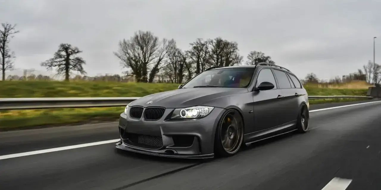 Szare BMW kombi pędzi autostradą, czuć jego prędkość.