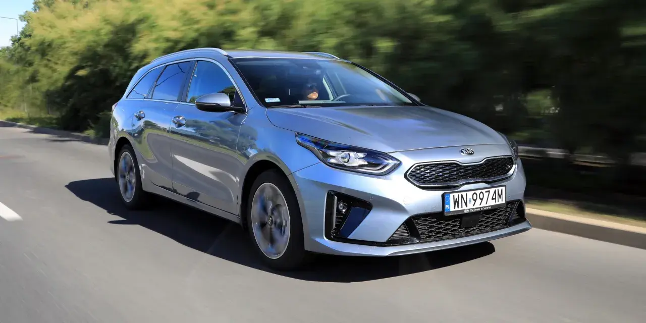 Srebrny Kia Ceed 1.6 benzyna w wersji kombi pędzi po drodze, otoczony zielenią.