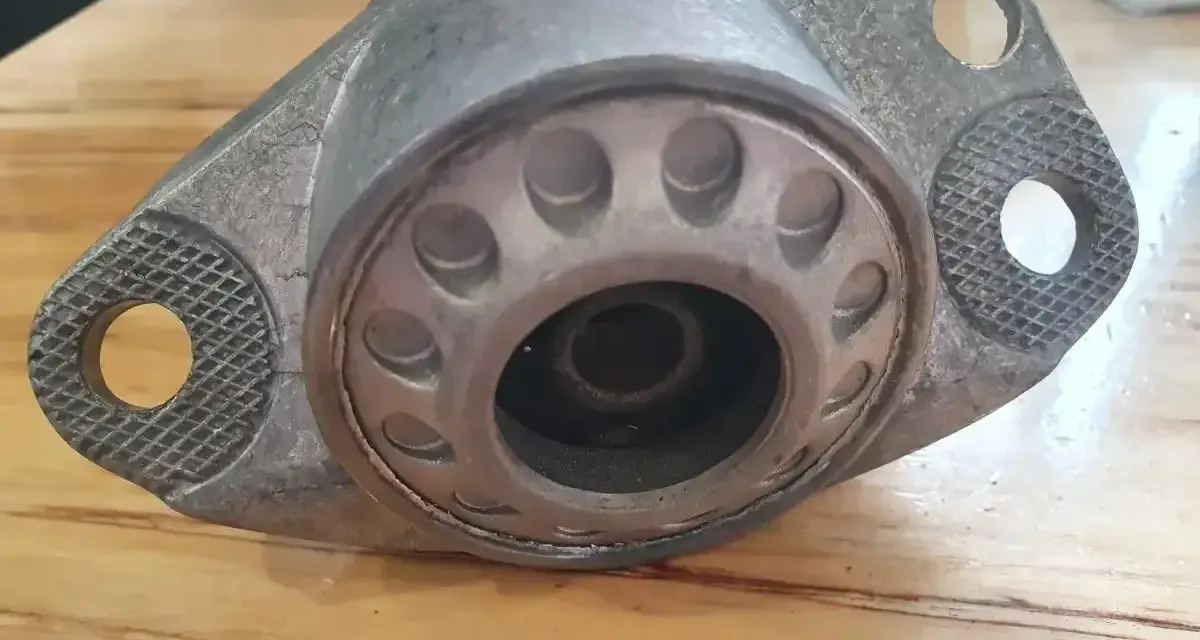 Metalowa poduszka amortyzatora z widocznymi pęknięciami, wskazującymi na objawy zużycia.