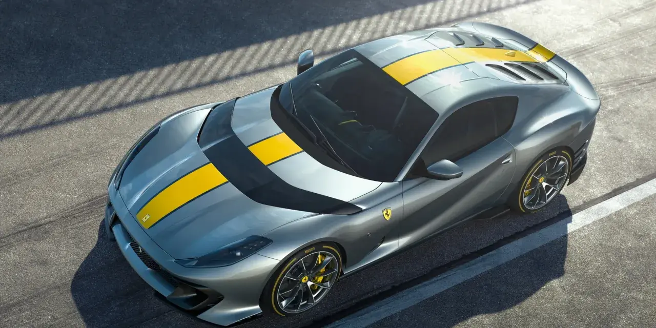 Szary Ferrari 812 Superfast z żółtymi pasami na masce i dachu, gotowy do szaleństwa na torze.