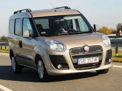 Złoty Fiat Doblo Maxi jedzie autostradą. Kierowca trzyma telefon.