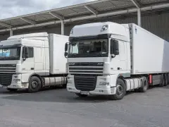 Dwa białe ciągniki siodłowe DAF XF, gotowe do trasy. Posiadanie prawa jazdy kat C+E otwiera drogę do takich pojazdów.