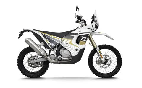 Biało-złoty motocykl Kove 450 Rally z owiewką i oponami terenowymi.