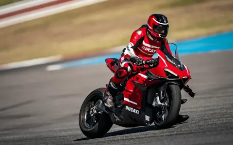 Motocyklista w czerwonym kombinezonie śmiga na torze wyścigowym na swoim czerwonym Ducati Panigale V4.