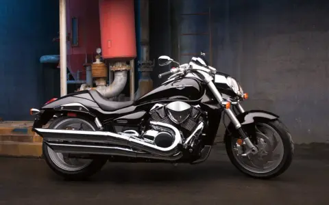 Czarny Suzuki Boulevard 1800 lśni w blasku przemysłowego otoczenia. Potężny silnik i chromowane detale przyciągają wzrok.