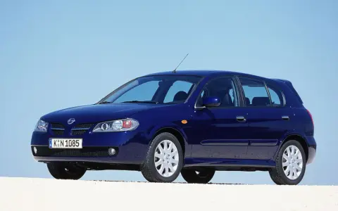 Granatowy Nissan Almera stoi na białym tle, z błękitnym niebem w tle.
