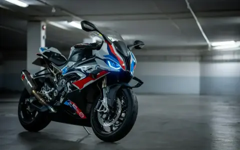 Sportowy motocykl BMW XR w barwach M, z niebieskimi światłami LED, gotowy do jazdy po torze.