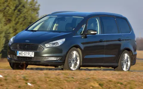 Ciemnozielony Ford Galaxy MK3 w ruchu, z polską tablicą rejestracyjną WE 019LF, przemierza wiejskie drogi.