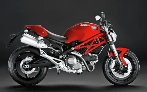 Czerwony Ducati Monster 696 z charakterystyczną kratownicową ramą, błyszczącym wydechem i sportowym siedzeniem.