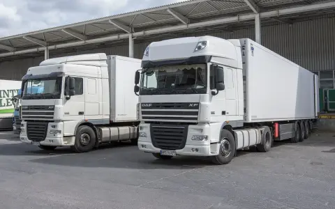 Dwa białe ciągniki siodłowe DAF XF, gotowe do trasy. Posiadanie prawa jazdy kat C+E otwiera drogę do takich pojazdów.