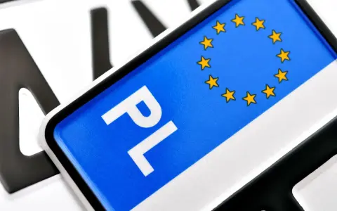 Zbliżenie na polskie tablice rejestracyjne z symbolem UE. Litery "PL" i gwiazdki na niebieskim tle.