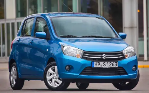 Niebieski Suzuki Celerio stoi przed nowoczesnym budynkiem.