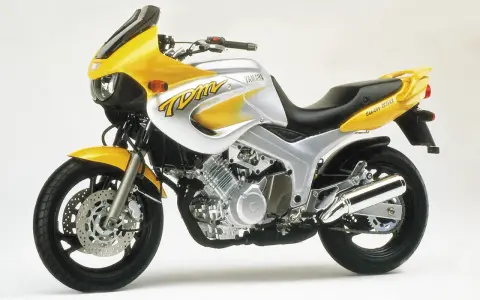 Żółto-srebrny motocykl Yamaha TDM 850 z charakterystycznym napisem "TDM" na baku. Gotowy na przygodę!