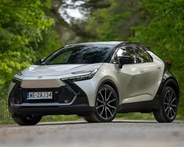 Nowa Toyota C-HR 2025 w kolorze srebrno-czarnym, zaparkowana na leśnej drodze.