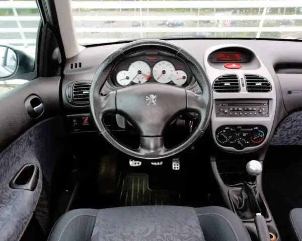 Wnętrze Peugeot 206 1.4 benzyna: kierownica, deska rozdzielcza z zegarami i radiem, dźwignia zmiany biegów, siedzenie.