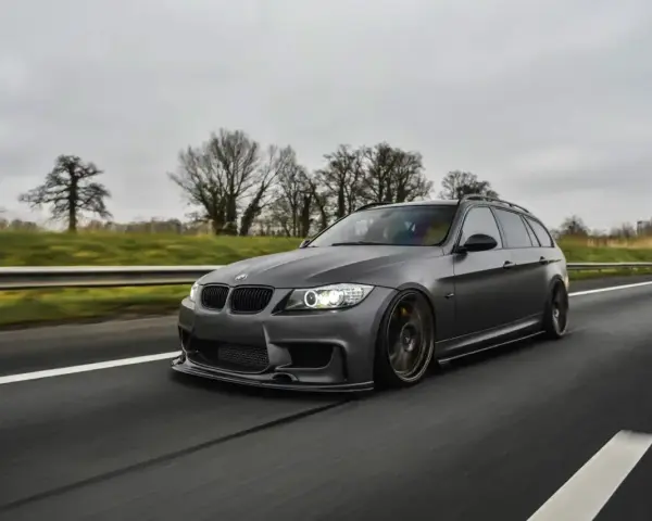 Szare BMW kombi pędzi autostradą, czuć jego prędkość.