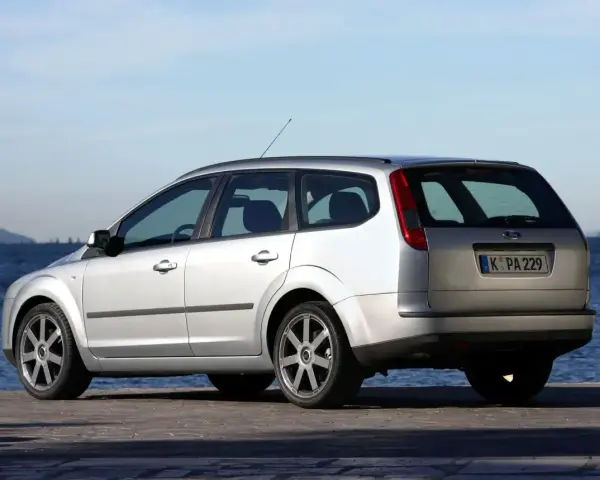 Srebrny Ford Focus MK2 1.6 benzyna kombi zaparkowany nad wodą.