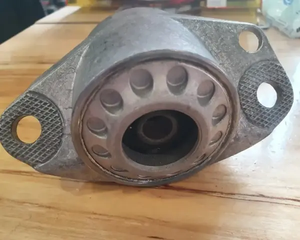 Metalowa poduszka amortyzatora z widocznymi pęknięciami, wskazującymi na objawy zużycia.