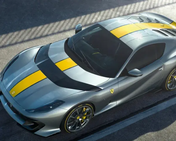 Szary Ferrari 812 Superfast z żółtymi pasami na masce i dachu, gotowy do szaleństwa na torze.