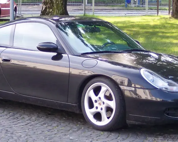 Czarny Porsche 996 z felgami w kolorze srebrnym stoi na bruku.