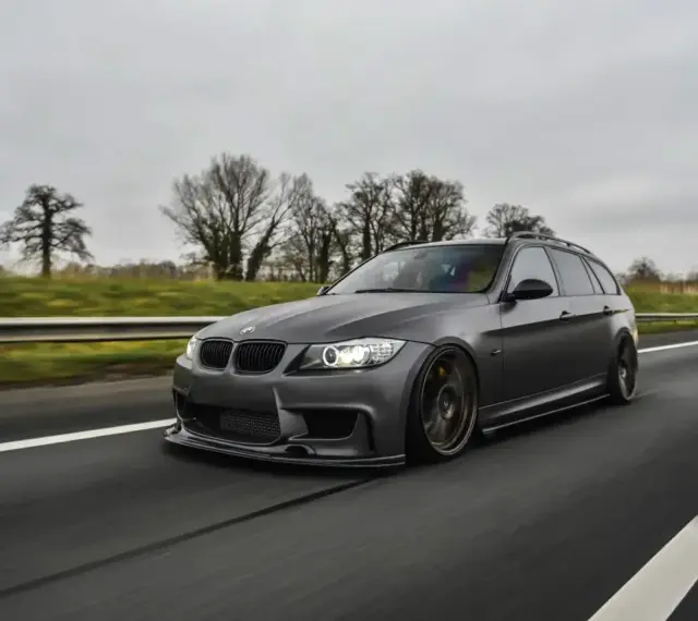 Szare BMW kombi pędzi autostradą, czuć jego prędkość.