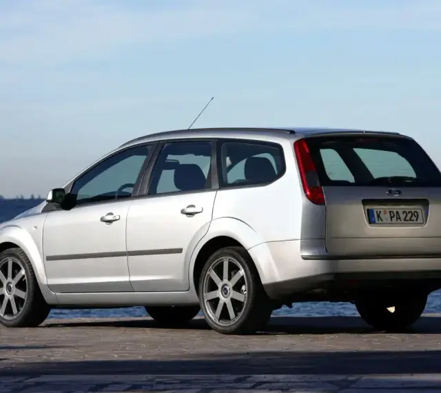 Srebrny Ford Focus MK2 1.6 benzyna kombi zaparkowany nad wodą.