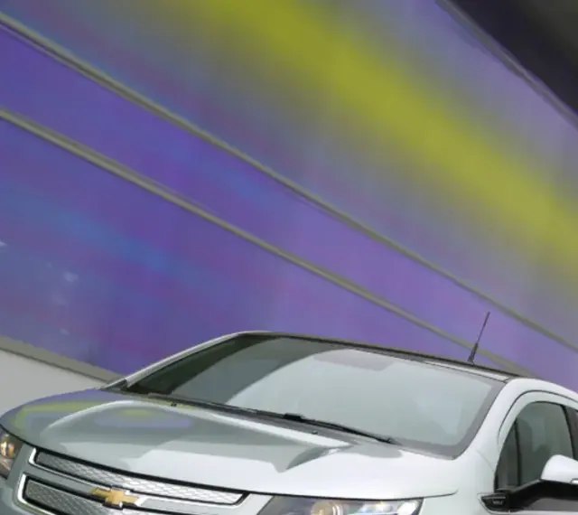 Srebrny Chevrolet Volt z nowoczesnym designem na tle tęczowej ściany.