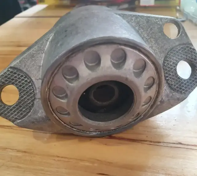 Metalowa poduszka amortyzatora z widocznymi pęknięciami, wskazującymi na objawy zużycia.