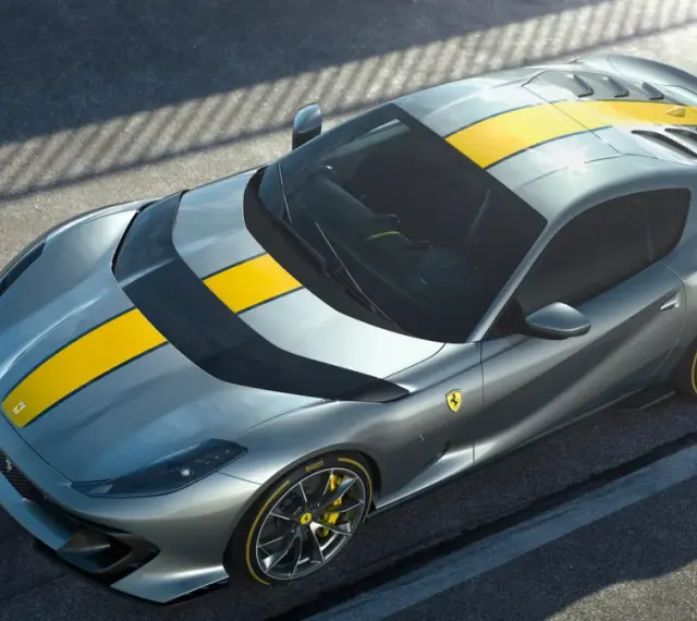 Szary Ferrari 812 Superfast z żółtymi pasami na masce i dachu, gotowy do szaleństwa na torze.