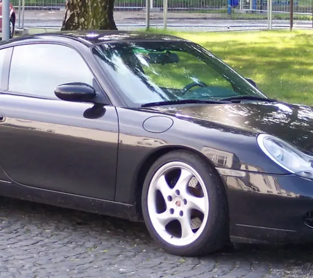 Czarny Porsche 996 z felgami w kolorze srebrnym stoi na bruku.