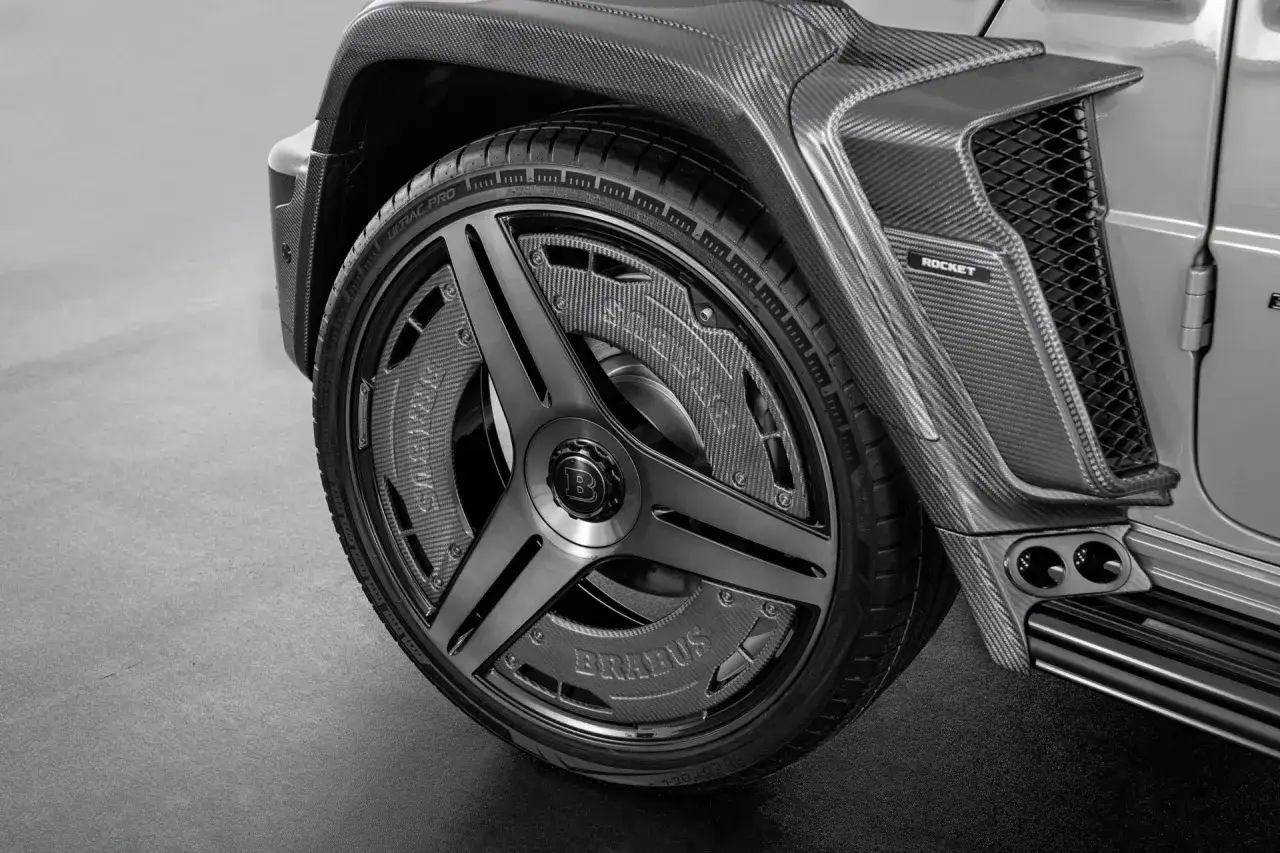 Zbliżenie na koło i błotnik Brabus Rocket 900 z włókna węglowego. Widoczne logo Brabus na zacisku hamulcowym.