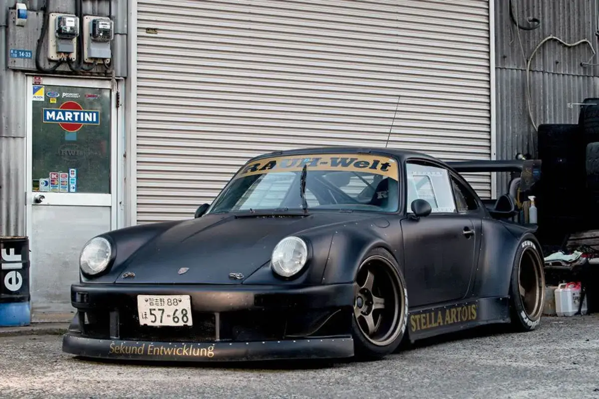 Czarny Porsche RWB z szerokimi błotnikami i spojlerem, z napisem 