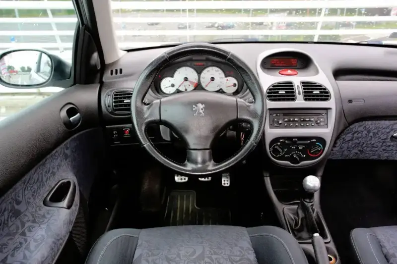 Wnętrze Peugeot 206 1.4 benzyna: kierownica, deska rozdzielcza z zegarami i radiem, dźwignia zmiany biegów, siedzenie.