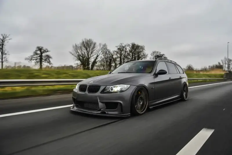 Szare BMW kombi pędzi autostradą, czuć jego prędkość.