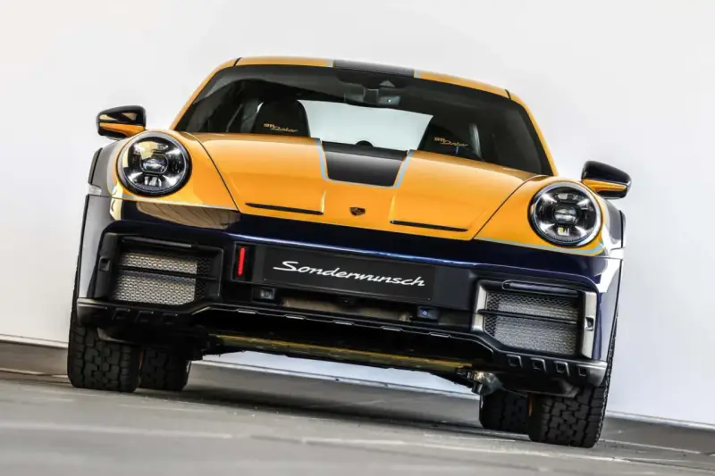 Żółto-granatowy Porsche 911 Dakar, gotowy na rajd dakar, z napisem "Sondermunsch" na zderzaku.