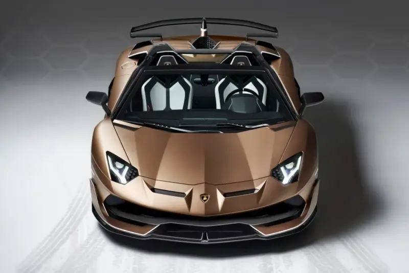 Brązowy Lamborghini Aventador SVJ z otwartym dachem, z czarnym spoilerem i białymi akcentami we wnętrzu, gotowy do jazdy.