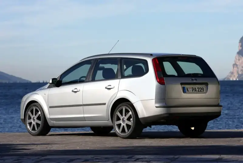 Srebrny Ford Focus MK2 1.6 benzyna kombi zaparkowany nad wodą.