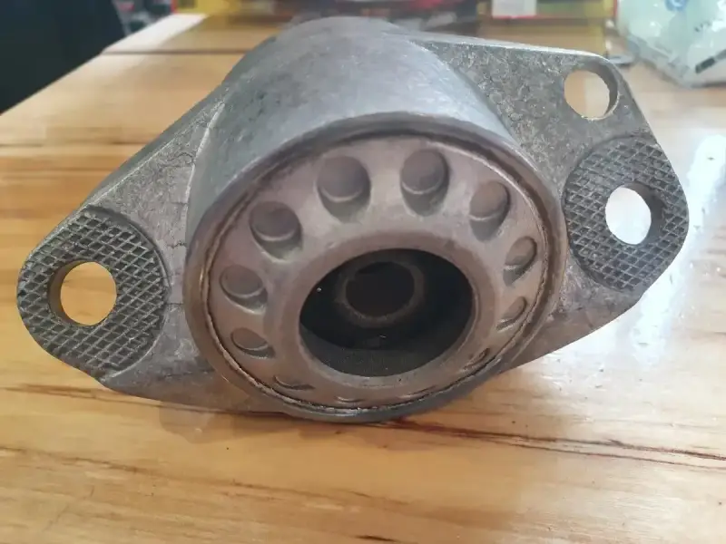 Metalowa poduszka amortyzatora z widocznymi pęknięciami, wskazującymi na objawy zużycia.