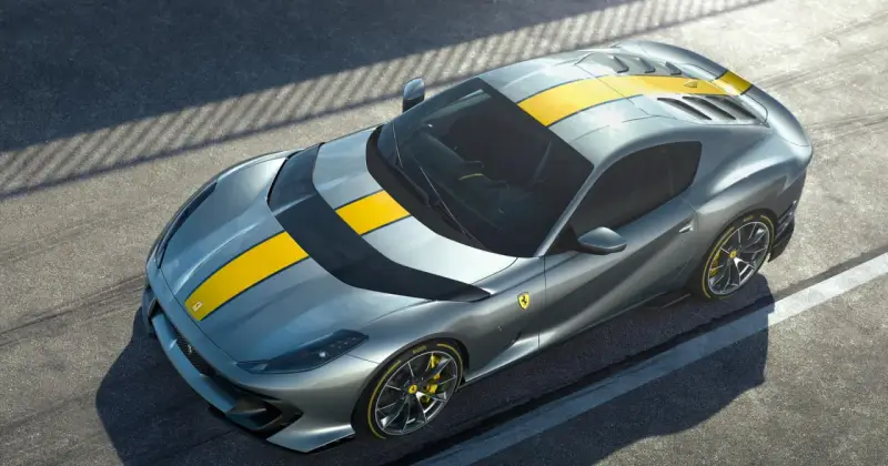 Szary Ferrari 812 Superfast z żółtymi pasami na masce i dachu, gotowy do szaleństwa na torze.