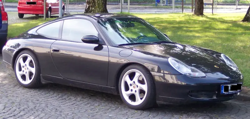 Czarny Porsche 996 z felgami w kolorze srebrnym stoi na bruku.